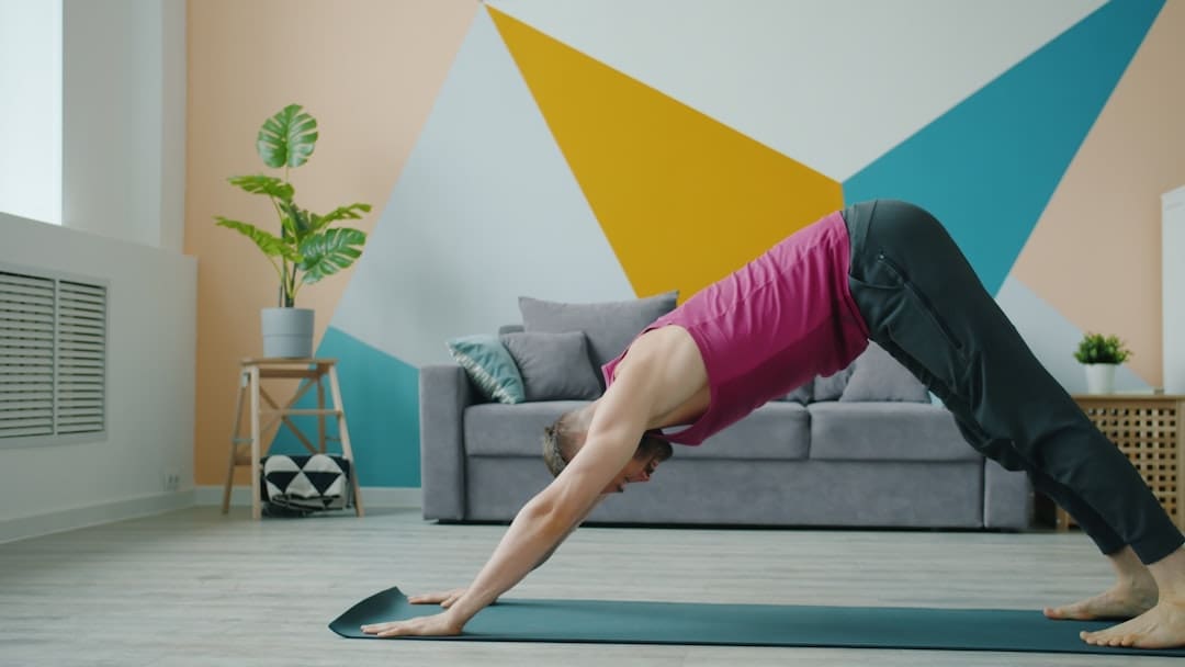 sick service dog — Man in downward dog pose on yoga mat indoors.